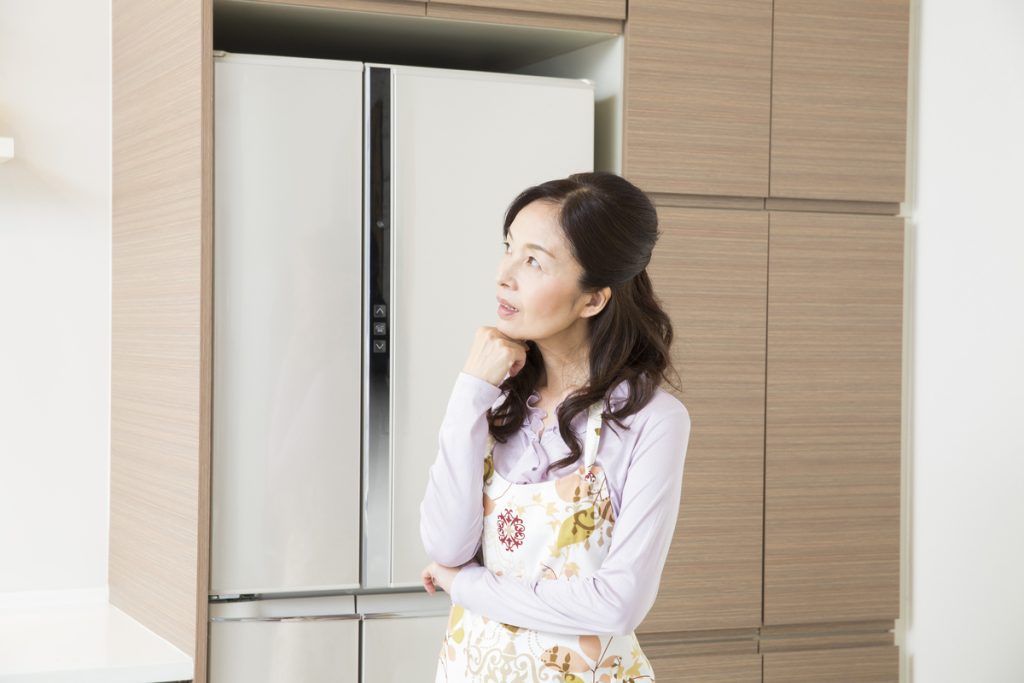 冷蔵庫の前で思案する女性