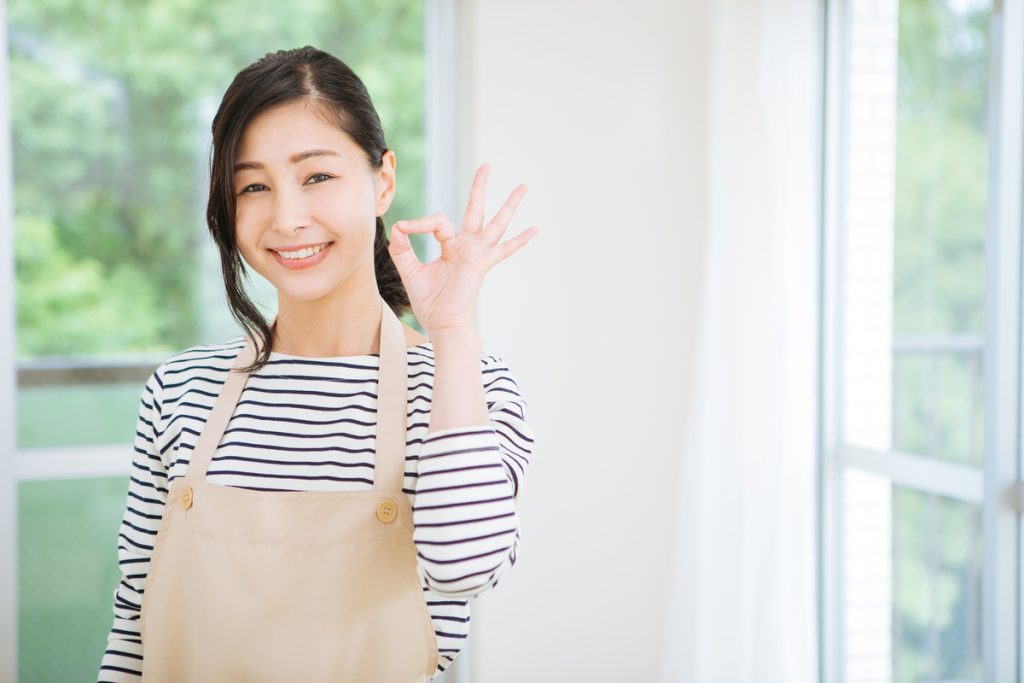 OKサインを出すエプロンの女性