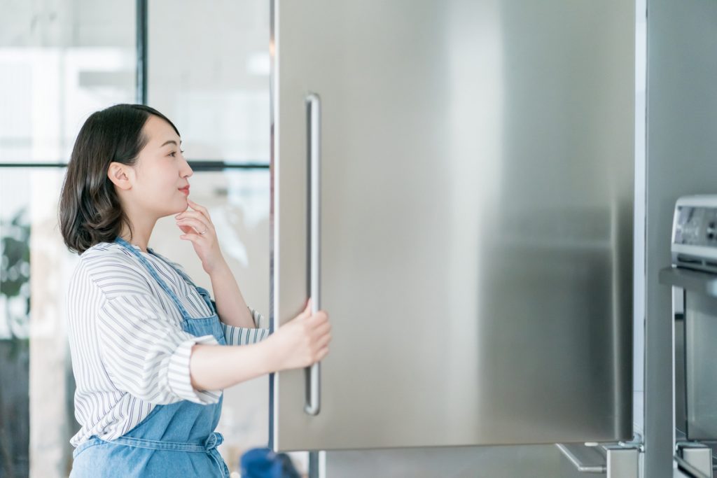 冷蔵庫を開けて献立を考える女性