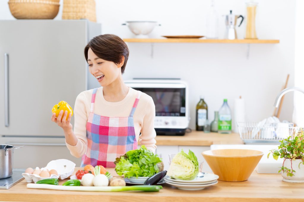 冷蔵庫の前で調理をする女性