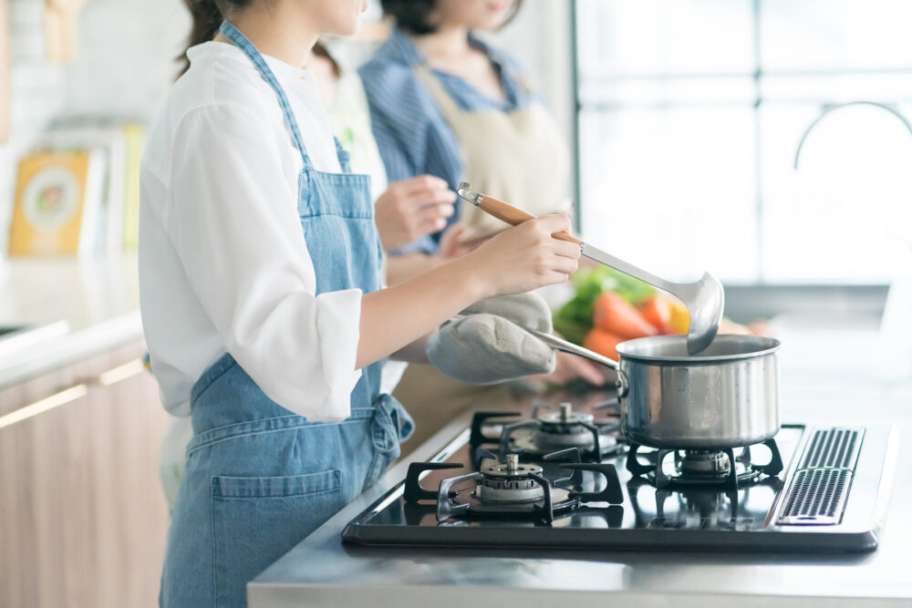 ガスコンロで調理する女性