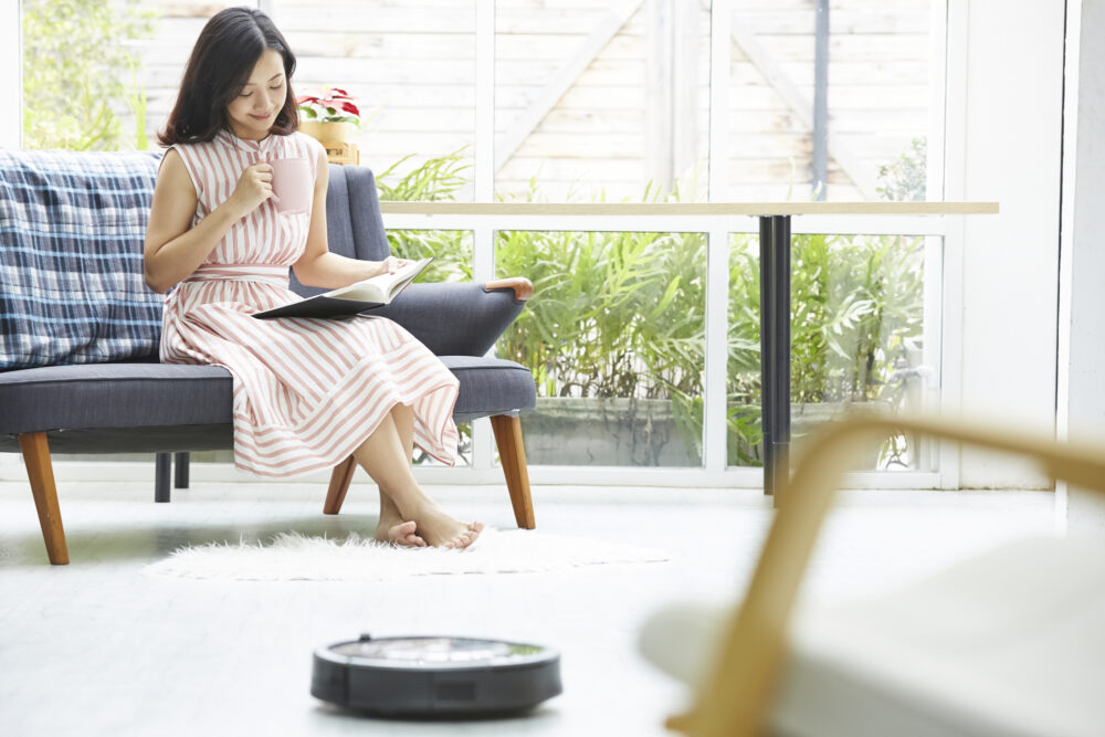 本を読む女性とロボット掃除機