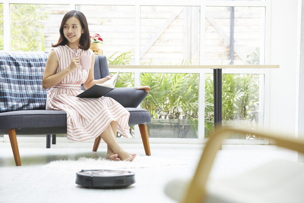 ロボット掃除機とソファに座る女性