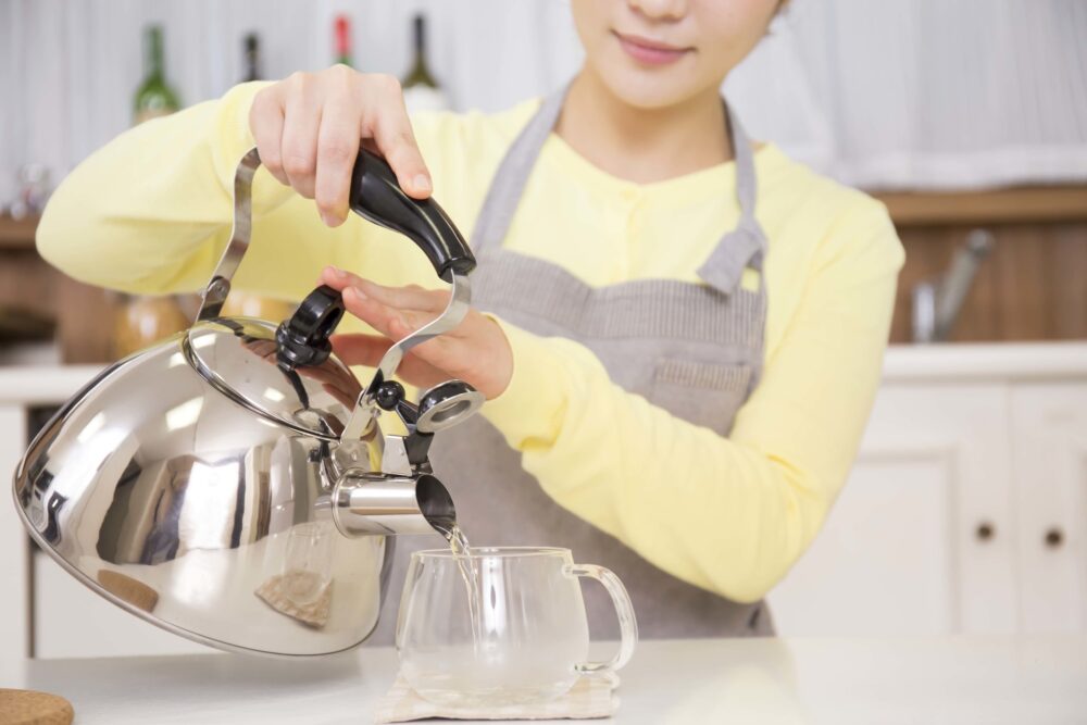 やかんのお湯をカップに注ぐ女性